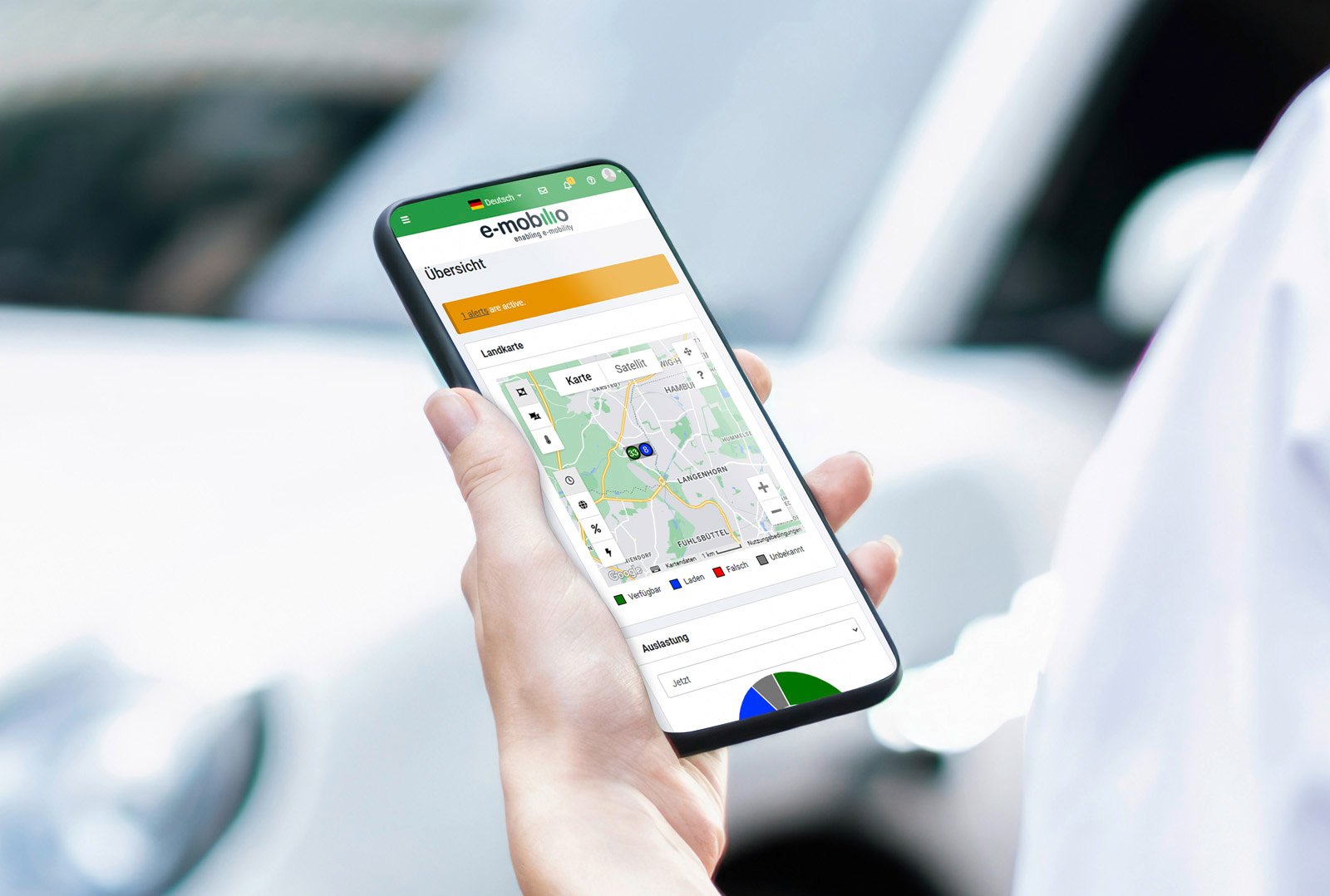 Person hält Smartphone mit geöffneter e-mobilio App – Übersichtskarte mit Ladestationen und Auswertungen zur Ladeinfrastruktur