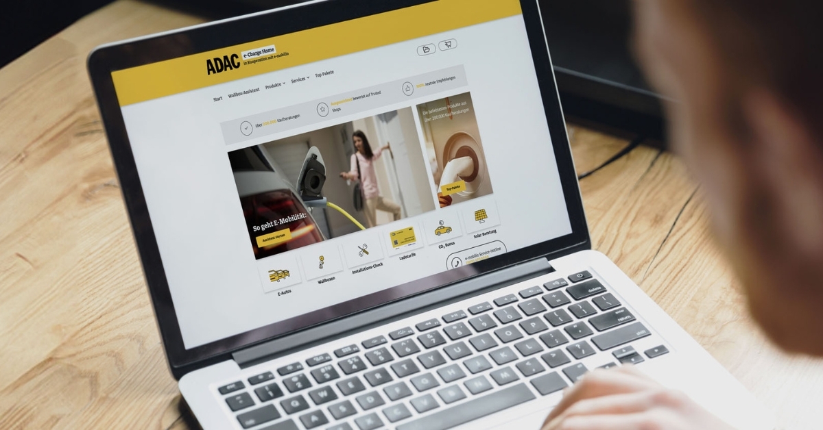 Ansicht von links hinten von einem Mann, der einen Laptop ansieht, auf dem der Blogartikel des ADAC bezüglich der Kooperation mit e-mobilio angezeigt wird